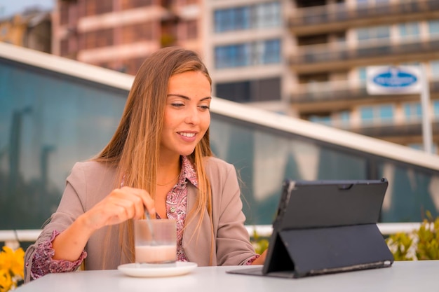 Femme d'affaires blonde ou femme financière prenant un petit-déjeuner au café décaféiné avec sa tablette