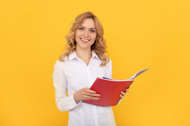 Femme d'affaires blonde heureuse en chemise blanche prenant des notes dans un bloc-notes ou un cahier, étudiant.