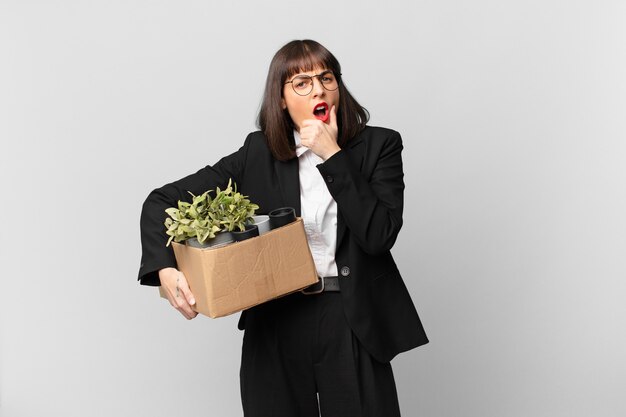 Femme d'affaires avec la bouche et les yeux grands ouverts et la main sur le menton, se sentant désagréablement choquée, disant quoi ou wow