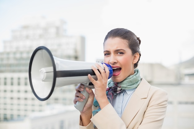 Femme d&#39;affaires brune aux cheveux brune irritée à l&#39;aide d&#39;un mégaphone