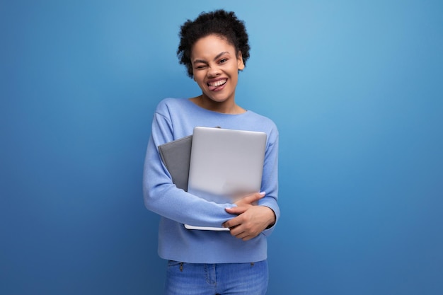 Femme d'affaires brune jeune cheveux afro réussie travaillant à l'aide d'un ordinateur portable