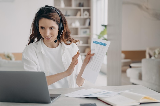 Une femme d'affaires caucasienne dans un casque signale une session Internet d'entreprise en ligne sur un ordinateur portable