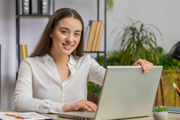 Une femme d'affaires caucasienne indépendante au bureau commence à travailler sur un ordinateur portable envoie des messages en ligne