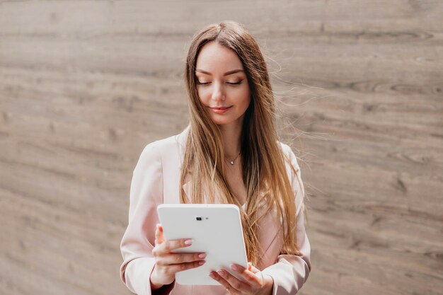 Photo femme d'affaires caucasienne souriante debout à l'extérieur près d'un immeuble de bureaux et tenant une tablette