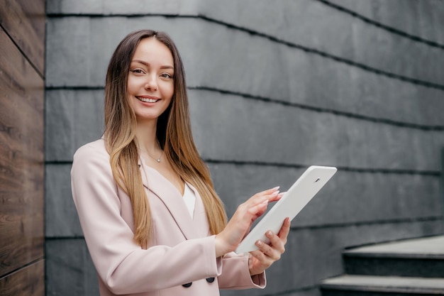 Femme d'affaires caucasienne souriante debout et tenant une tablette