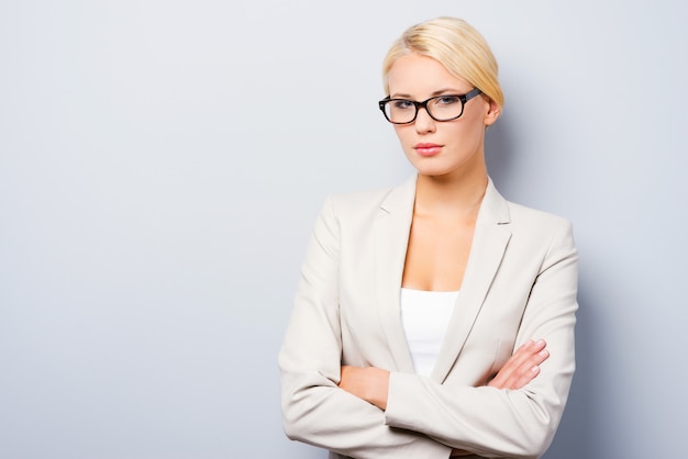 Femme d'affaires charmante. Jeune femme d'affaires confiante gardant les bras croisés et regardant la caméra