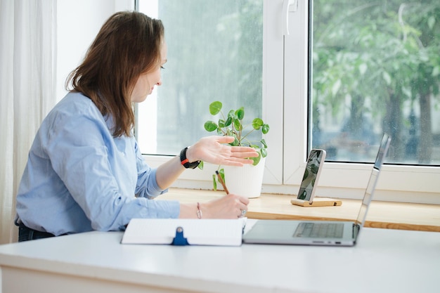 Femme d'affaires en chemise bleue assis derrière le bureau avec un ordinateur portable