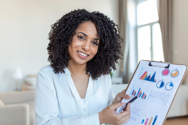 Femme d'affaires ciblée présentant des tableaux et des graphiques lors d'un appel vidéo en ligne Jeune femme d'affaires ayant une conférence téléphonique avec un client sur un ordinateur portable