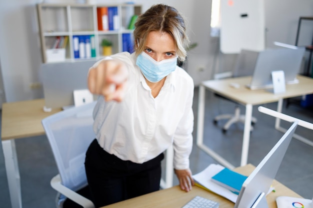 Une femme d'affaires en colère dans un masque demande à quitter le bureau