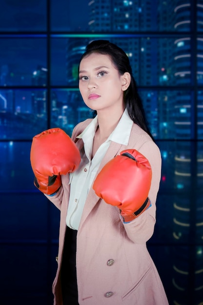 Photo une femme d'affaires en colère porte des gants de boxe au bureau.