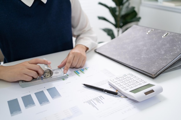 Femme d'affaires comptable analysant les graphiques d'investissement Facture et appuyant sur les boutons de la calculatrice sur les documents