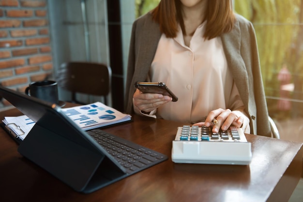 Femme d'affaires ou comptable main tenant un stylo travaillant pour calculer le bureau xAon sur le coût au bureau à domicile