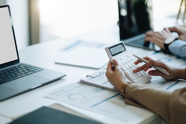 Femme d'affaires comptable travaillant à la main sur la calculatrice pour calculer le document de comptabilité du rapport de données financières et l'ordinateur portable au concept d'entreprise de bureau