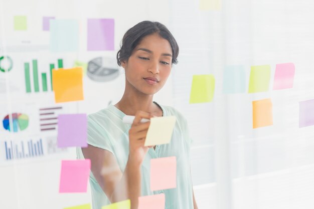 Femme d&#39;affaires concentré à la recherche de son poste sur le mur