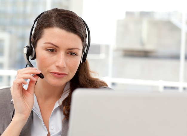 Femme d&#39;affaires concentré travaillant sur son ordinateur portable tout en appelant