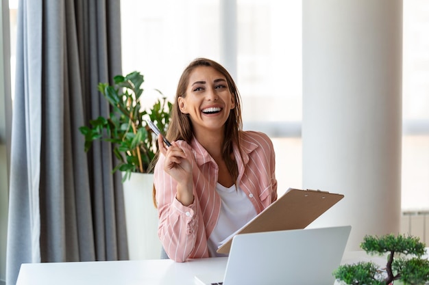 Femme d'affaires concentrée utilisant un ordinateur portable à la maison en regardant l'écran bavarder en lisant ou en écrivant des e-mails assis sur un canapé une étudiante sérieuse faisant ses devoirs travaillant sur un projet de recherche en ligne