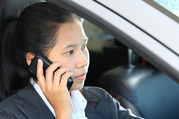 Femme d&#39;affaires conduisant une voiture et parlant un téléphone