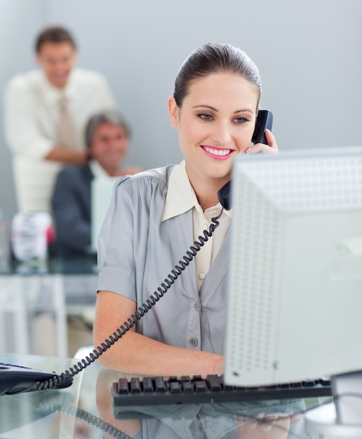 Photo femme d'affaires confiant au téléphone travaillant à un ordinateur