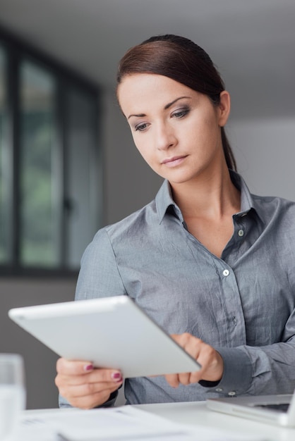 Femme d'affaires confiante à l'aide d'une tablette numérique