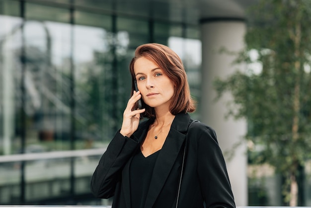 Une femme d'affaires confiante aux cheveux roux qui parle au téléphone portable.