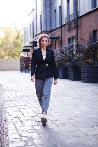 Photo femme d'affaires confiante dans des vêtements de bureau élégants veste noire walking street à la caméra