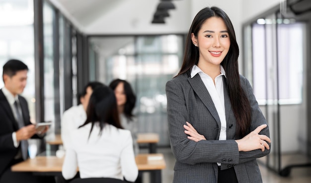 Femme d'affaires confiante souriante regardant la caméra et debout dans un bureau lors d'une réunion d'équipe