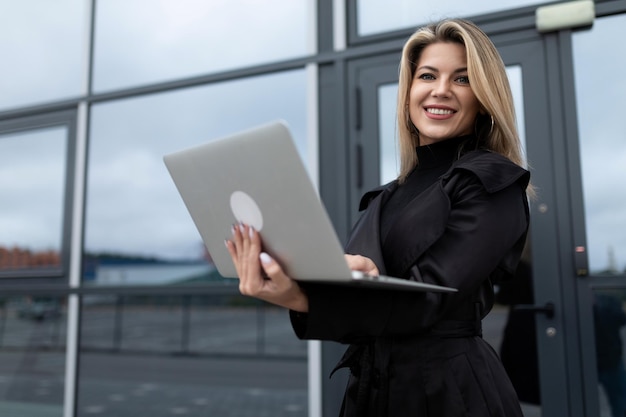 Une femme d'affaires confiante avec succès travaille en ligne sur un ordinateur portable dans le contexte d'un bureau