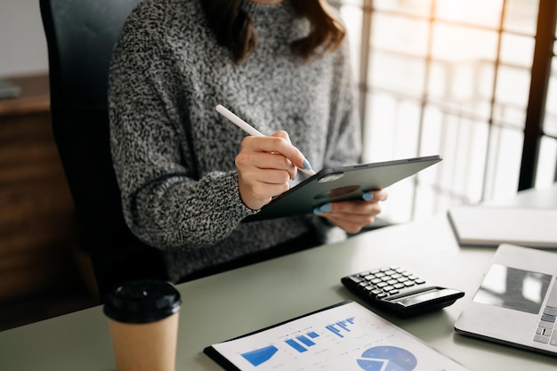 Femme d'affaires confiante travaillant sur un ordinateur portable, une tablette et une tablette sur son lieu de travail au bureau modernexA