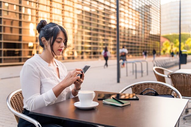 Femme d'affaires consultant son téléphone sur la terrasse d'un café, concept d'entrepreneur numérique et mode de vie urbain, espace de copie pour le texte