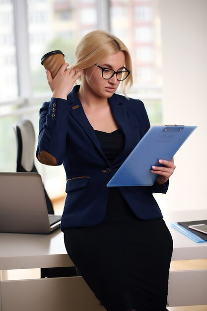 Femme d'affaires en costume assis au bureau avec ordinateur portable.