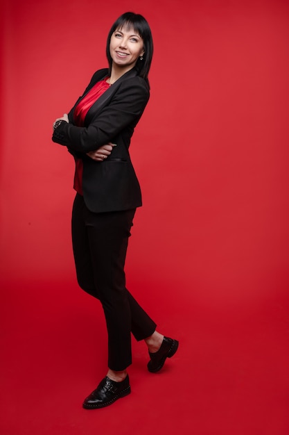 Femme d'affaires en costume noir et chaussures rouges.