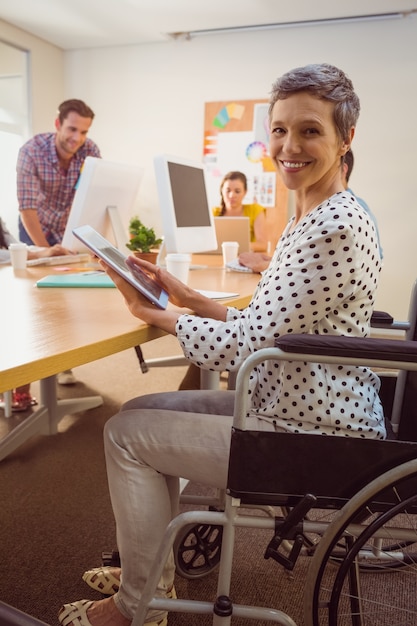 Femme d&#39;affaires créative en fauteuil roulant à l&#39;aide d&#39;une tablette