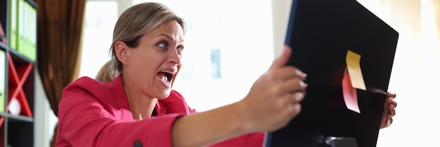 Photo femme d'affaires criant hystériquement à l'écran de l'ordinateur au bureau choquée femme financière