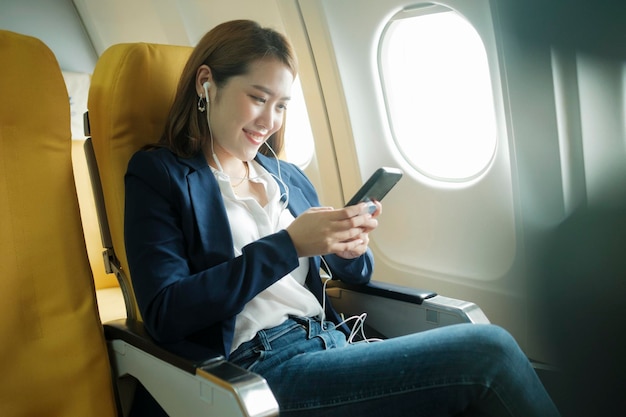 Femme d'affaires dans un avion travaille sur l'utilisation d'écouteurs téléphoniques