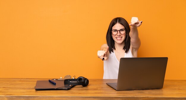 Femme d'affaires dans un bureau pointe du doigt sur vous en souriant