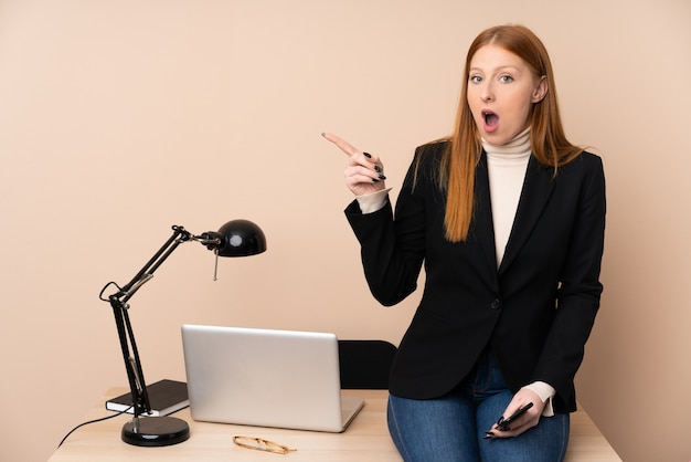 Femme d'affaires dans un bureau surpris et pointant le doigt sur le côté