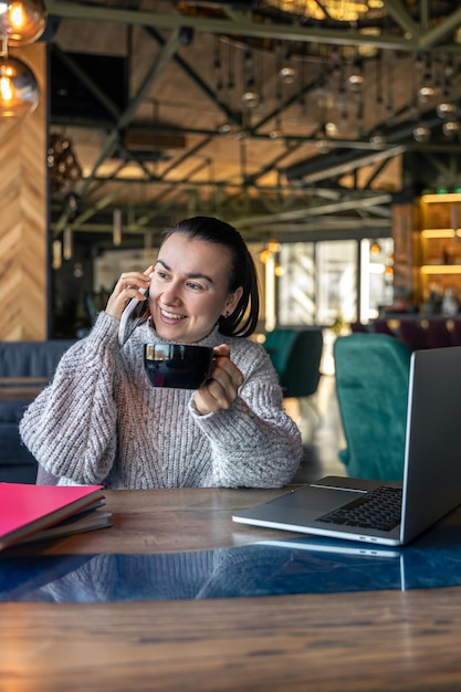 Femme d'affaires dans un café avec un ordinateur portable boit du thé