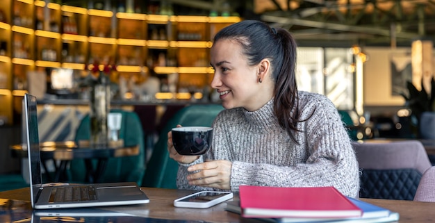 Femme d'affaires dans un café avec un ordinateur portable boit du thé