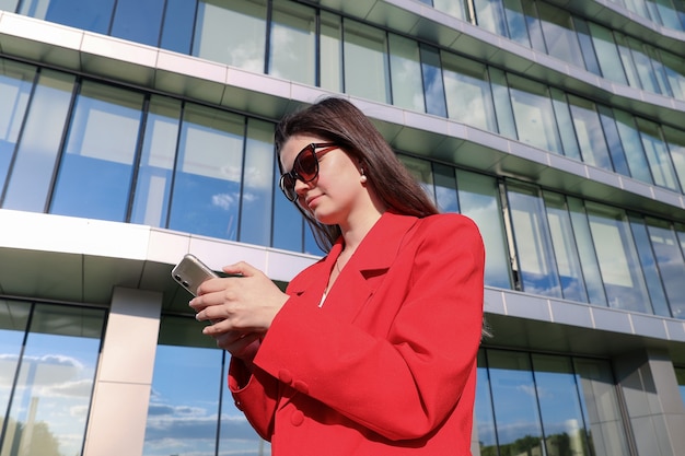 Femme d'affaires dans une veste en tapant au téléphone dans la rue