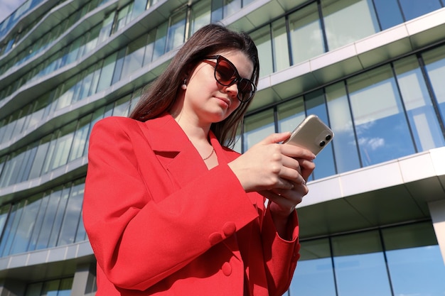 Femme d'affaires dans une veste tapant au téléphone dans la rue