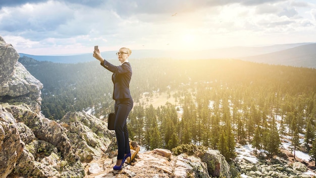 Femme d'affaires debout contre le paysage et faisant du selfie. Technique mixte