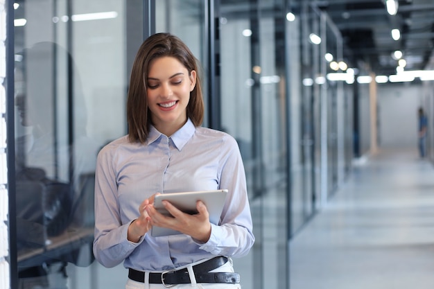 Femme d'affaires debout dans le hall et utilisant une tablette numérique.