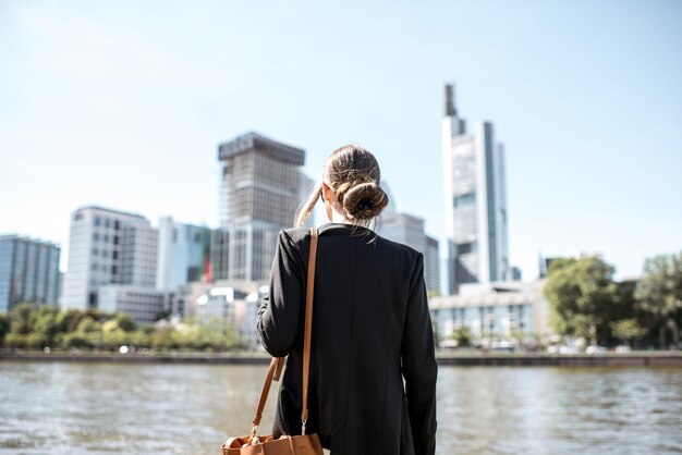 Femme d'affaires debout sur le quai avec une vue magnifique sur les gratte-ciel de la ville de Francfort