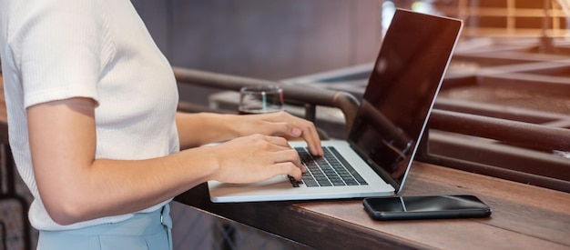 Femme d'affaires décontractée à l'aide d'un smartphone et d'un ordinateur portable femme indépendante tapant un clavier d'ordinateur portable dans un café ou une technologie de bureau moderne numérique en ligne et concept de réseau