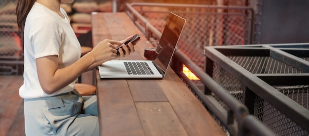 Femme d'affaires décontractée à l'aide d'un smartphone et d'un ordinateur portable femme indépendante tapant un clavier d'ordinateur portable dans un café ou une technologie de bureau moderne numérique en ligne et concept de réseau