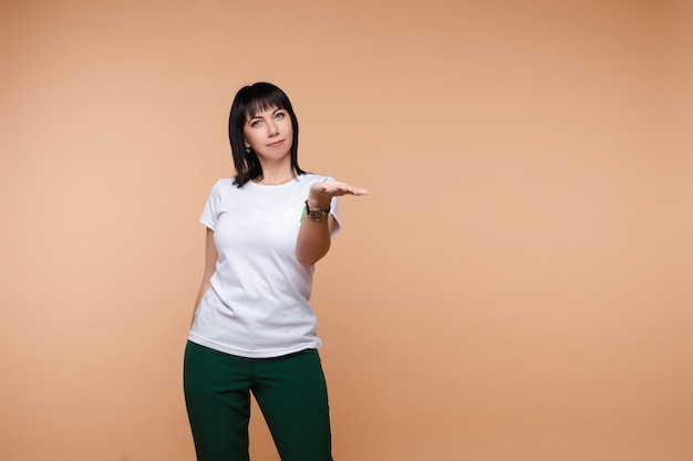 Femme d'affaires décontractée dans des verres montrant la main isolée sur fond de studio. Femme rousse souriante pointant sur place pour le texte posant en regardant la caméra