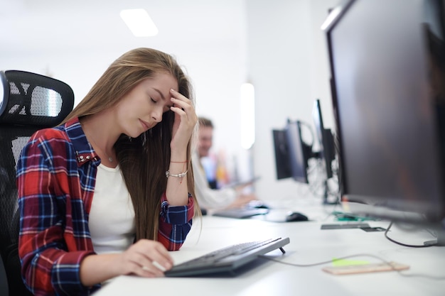 femme d'affaires décontractée fatiguée prenant une pause tout en travaillant sur un ordinateur de bureau dans un intérieur de bureau de démarrage à plan ouvert moderne Concept de stress de date limite