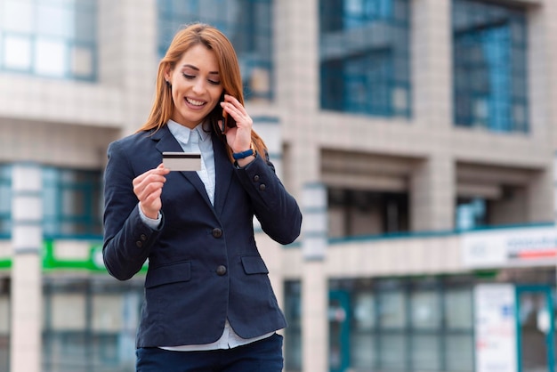 Femme d'affaires détenant une carte de crédit et un téléphone en plein air