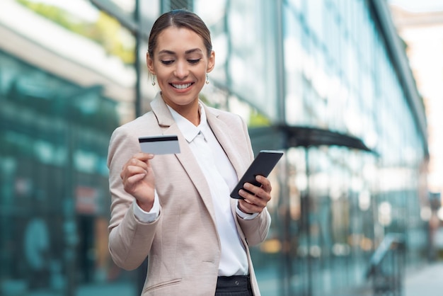 Femme d'affaires détenant une carte de crédit et utilisant un téléphone