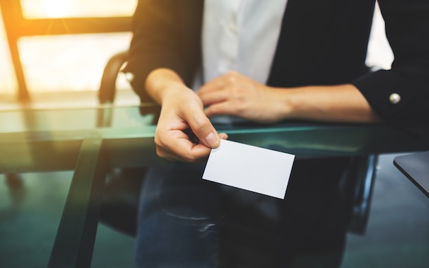 Femme d'affaires détenant et donnant une carte de visite vierge à quelqu'un